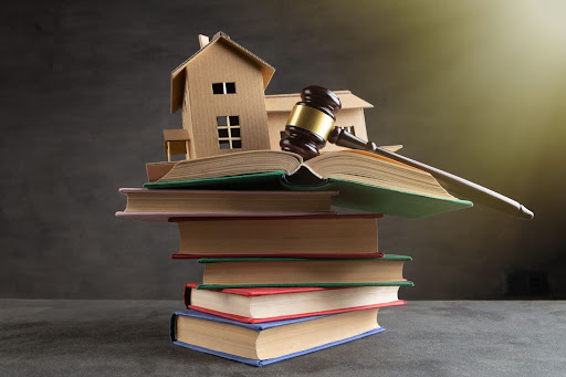 A house sits on a stack of books. It is to be auctioned.