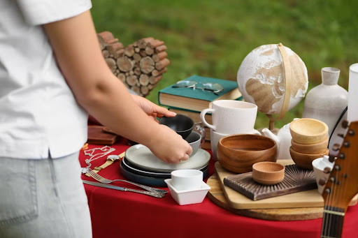 A woman browses old items on a table.